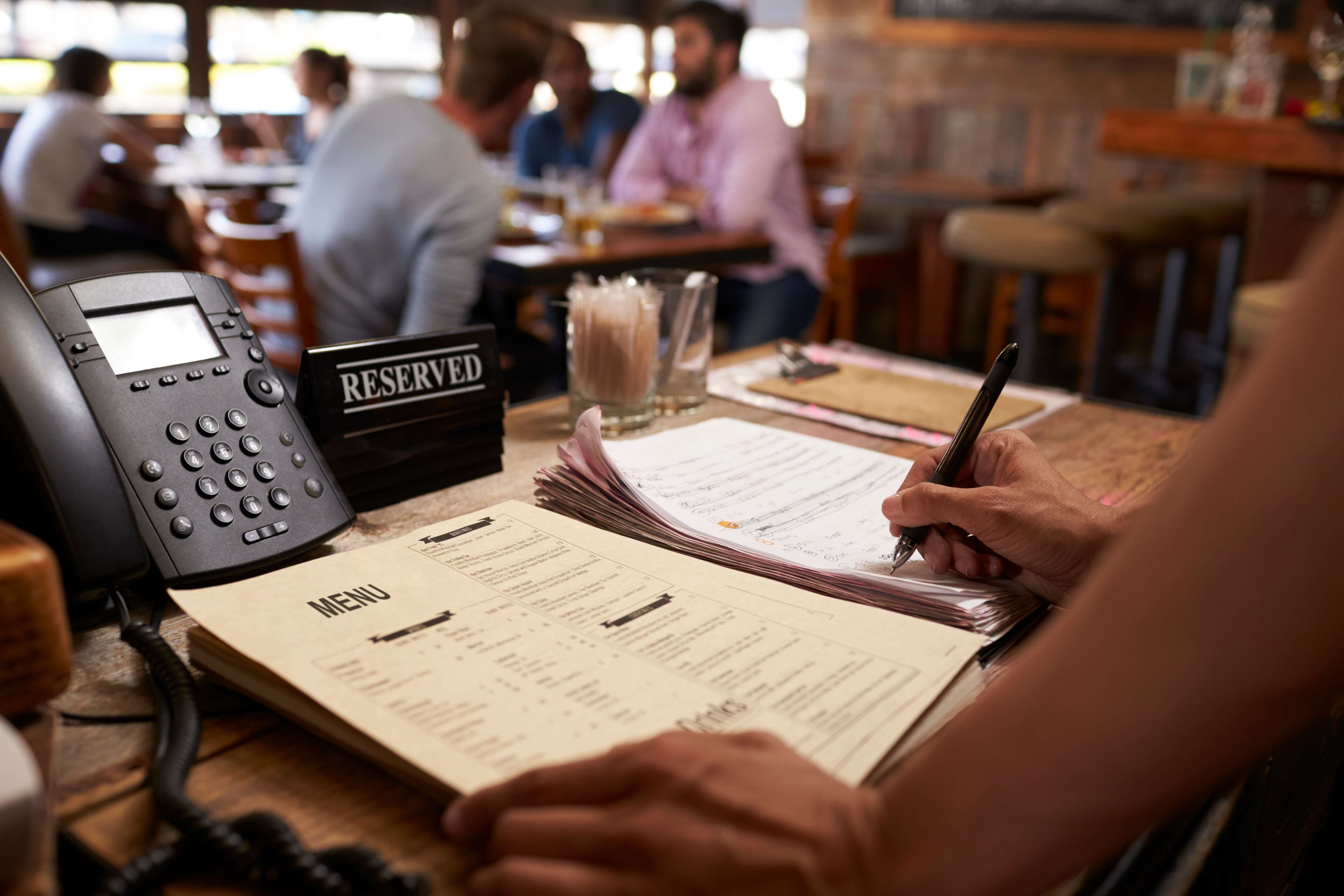 Restaurant manager handling reservations and business operations representing the comprehensive management aspects protected by restaurant insurance coverage