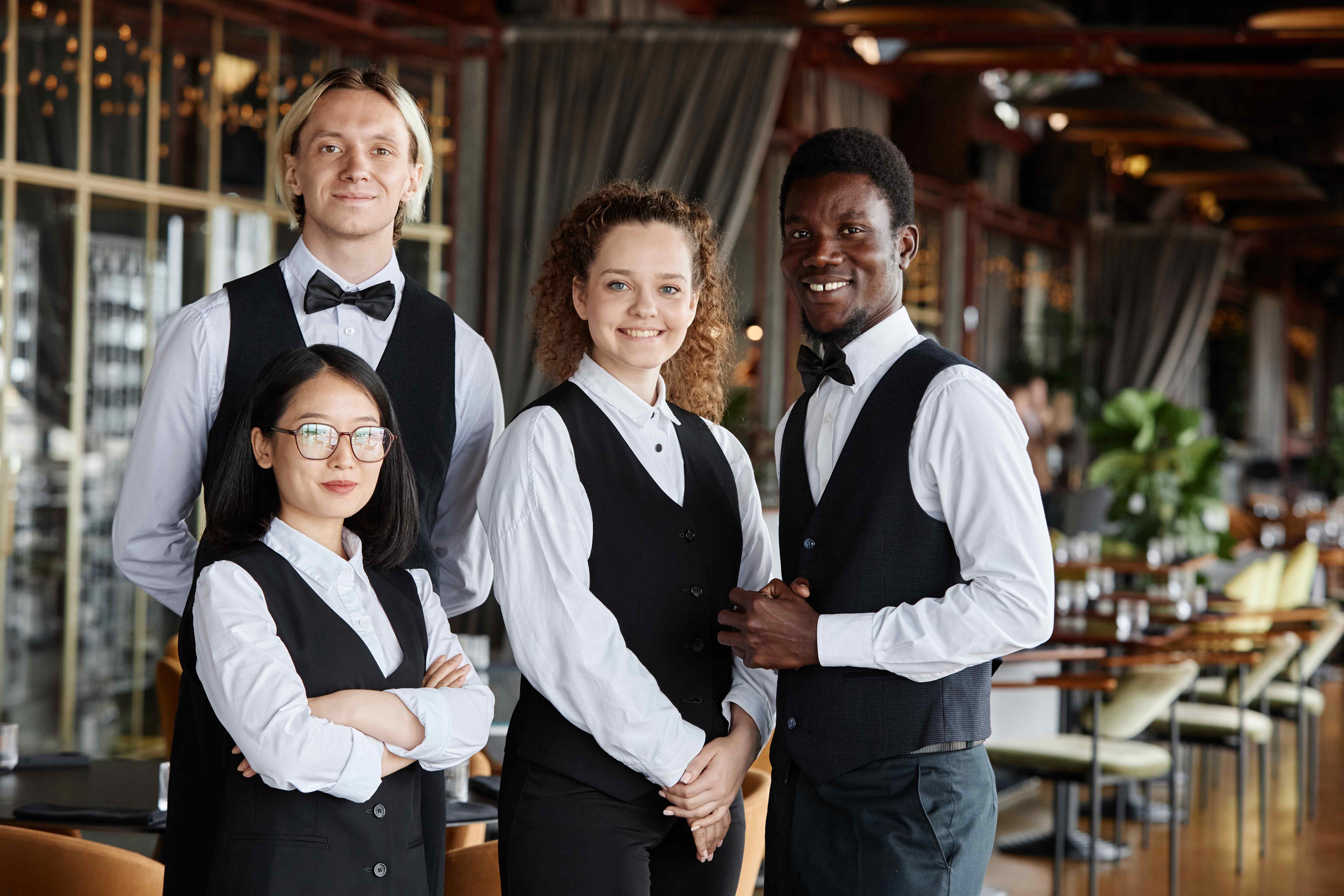 Professional diverse restaurant service team in formal uniforms representing the skilled staff protected by comprehensive restaurant insurance coverage