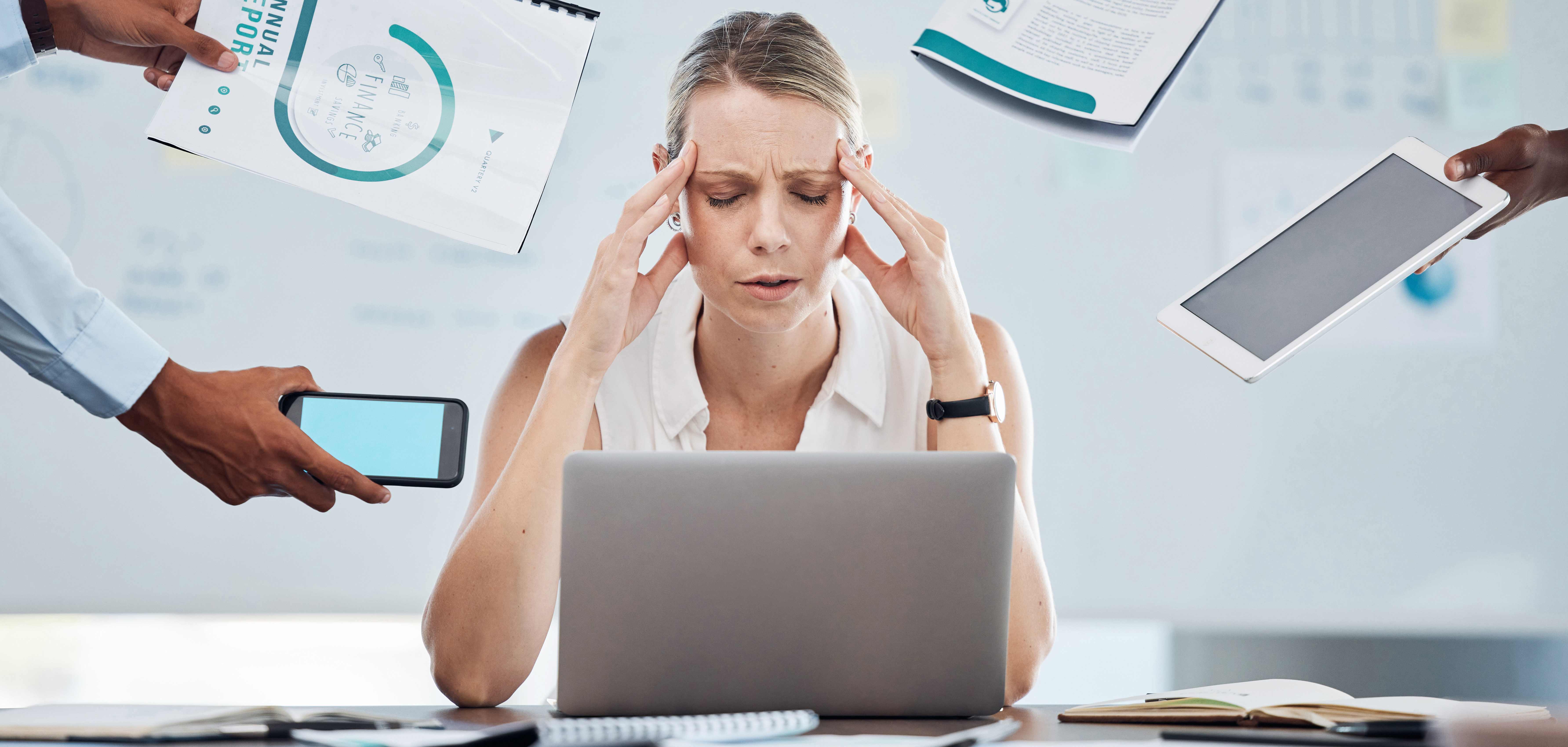 Stressed professional woman at desk surrounded by business documents and demands representing the need for errors and omissions insurance protection